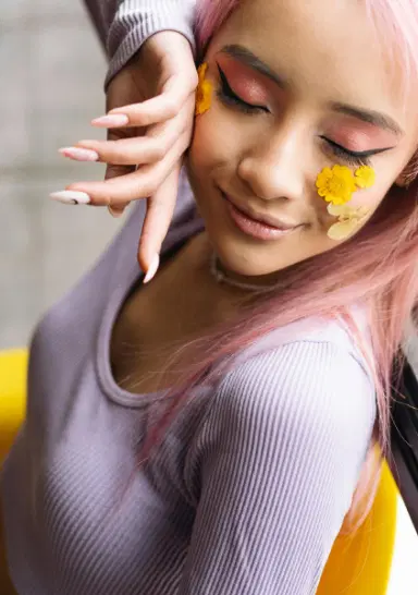 A person with pastel-pink hair with flowers under her eyes.