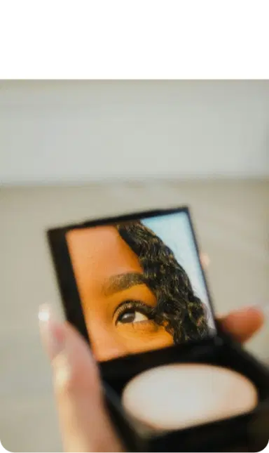 A hand holding a small mirror, reflecting an eye.